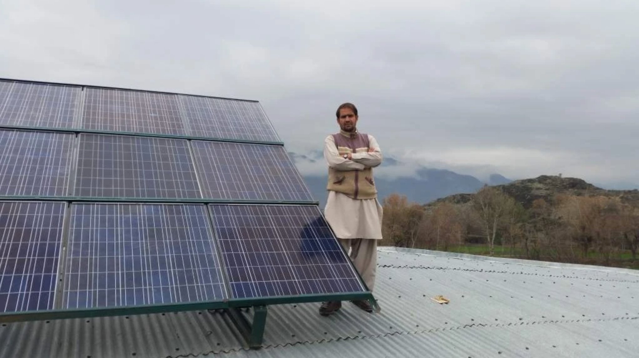 Community member standing with completed rooftop solar installation