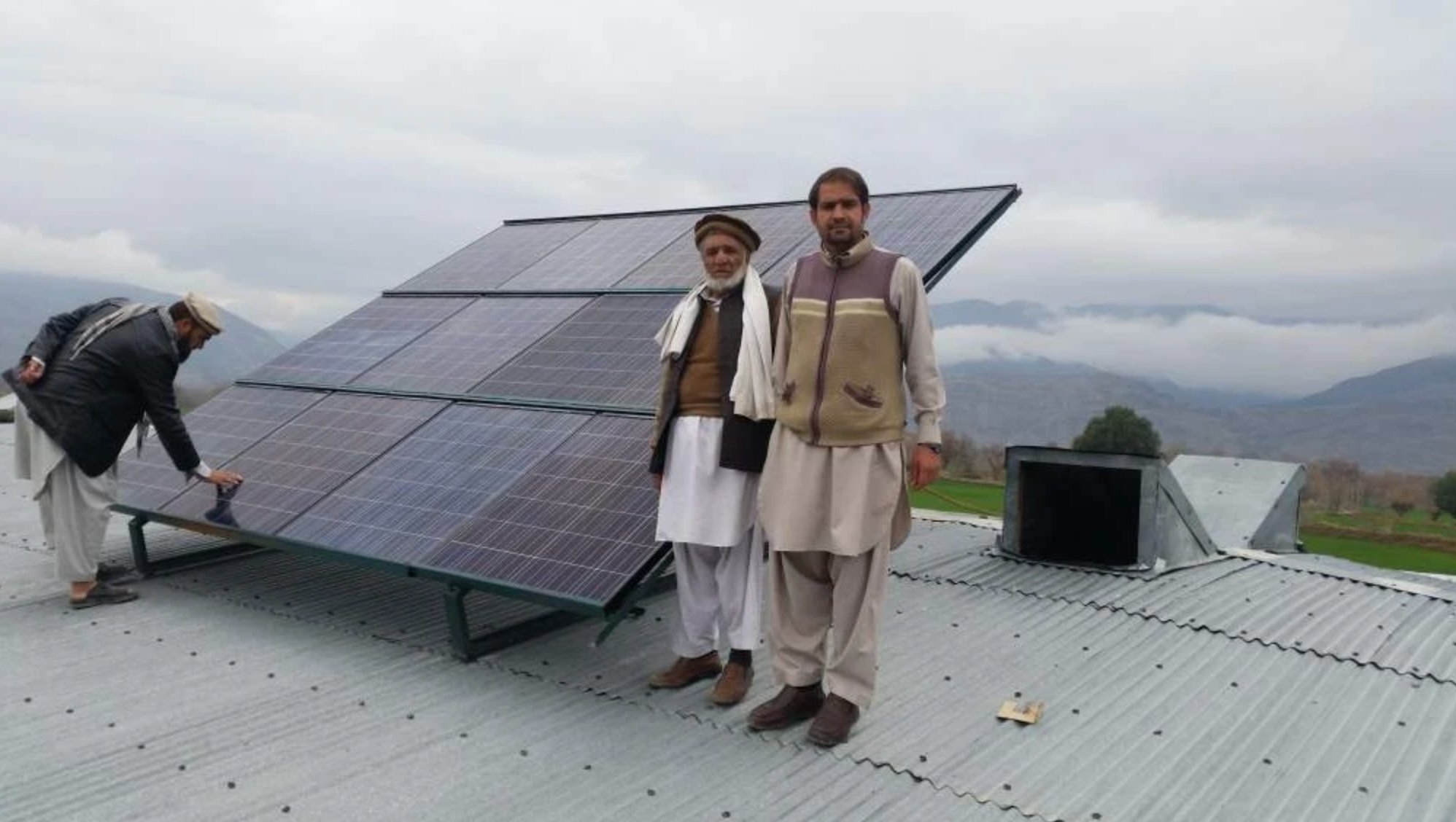 Community members with solar panels on school rooftop