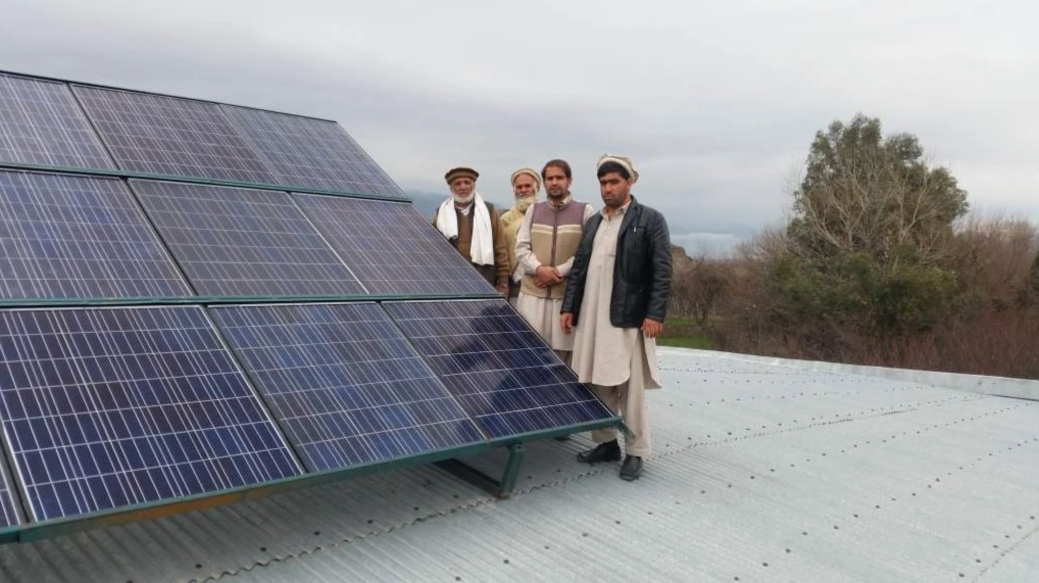 Group photo with solar panels at completed school project