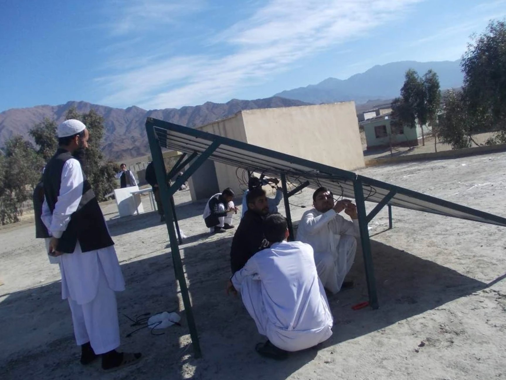 Workers wiring solar panels at school